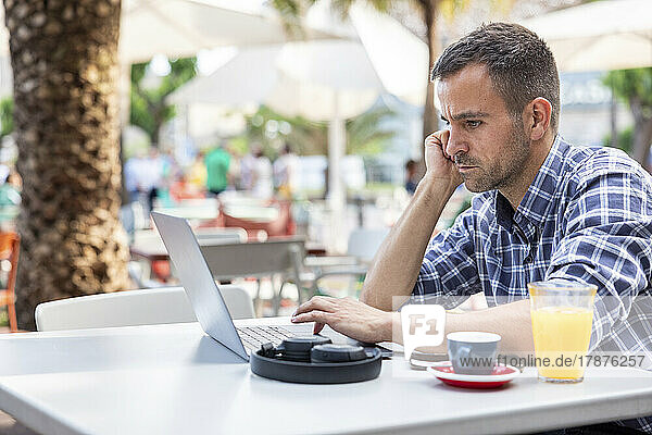 Mature freelancer using laptop sitting at cafe
