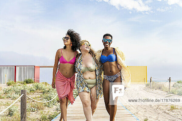 Carefree multiracial friends walking at beach
