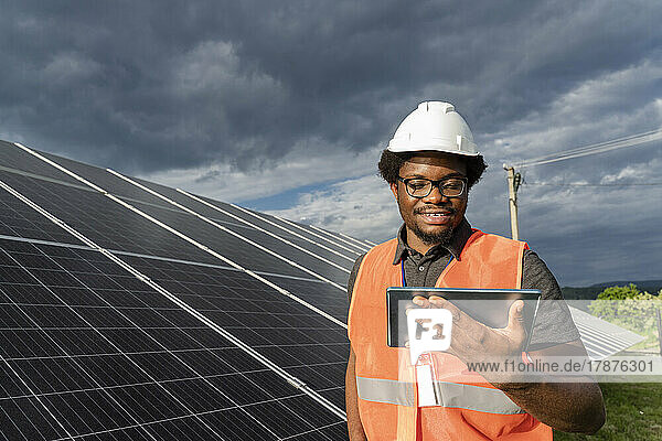 Smiling engineer using tablet PC at solar station
