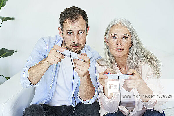Mother and son playing video game with game controllers at home