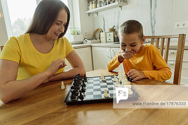 Smiling mother and son playing chess at home