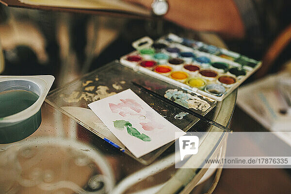 Color palette with paintbrush on table at home