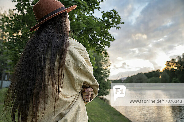 Woman in hat looking at sunset in park
