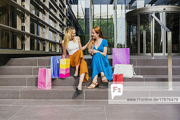 Women with shopping bags sitting on steps outside mall
