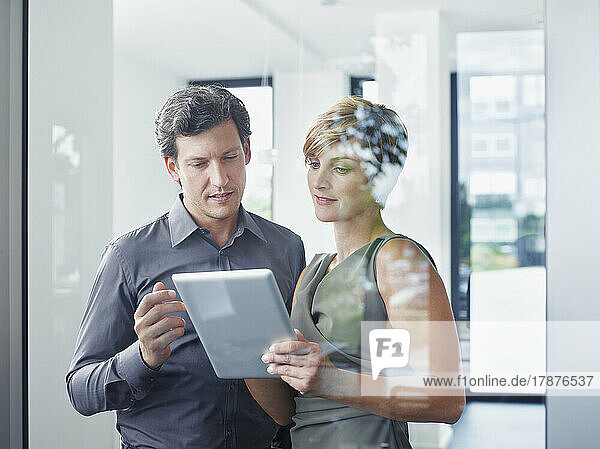 Businesswoman discussing with colleague over tablet PC