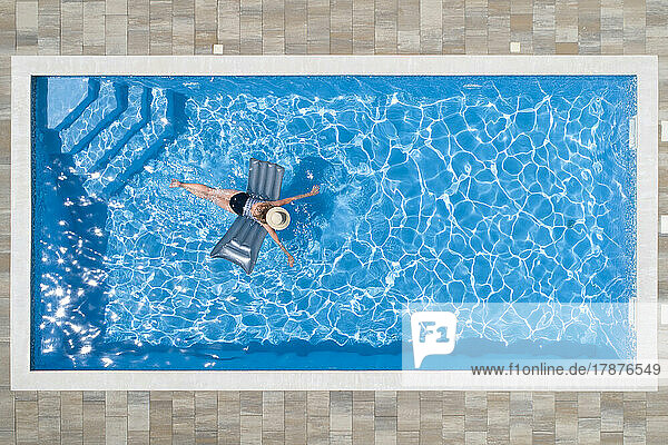 Woman swimming with pool raft in pool