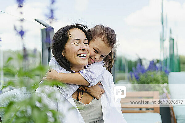 Cheerful woman giving piggyback to daughter