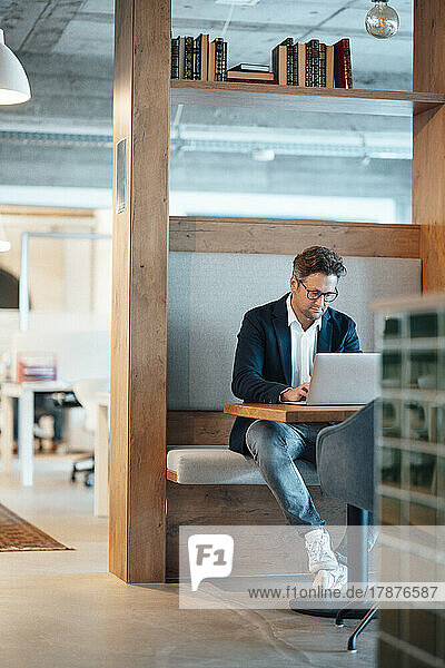 Mature businessman using laptop sitting at desk in office