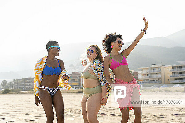 Multiracial friends dancing together at beach on vacation