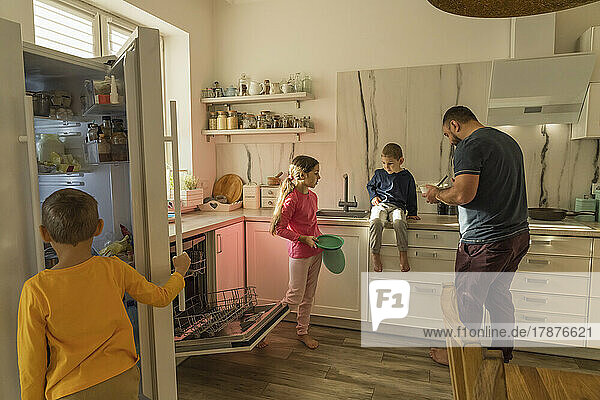 Girl and boys with father in kitchen at home
