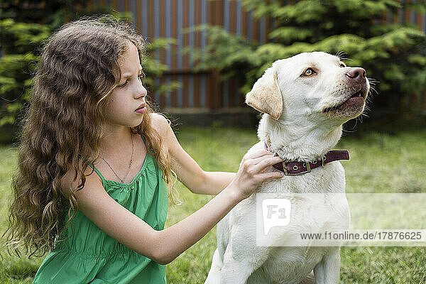 Girl adjusting dog's leash at back yard