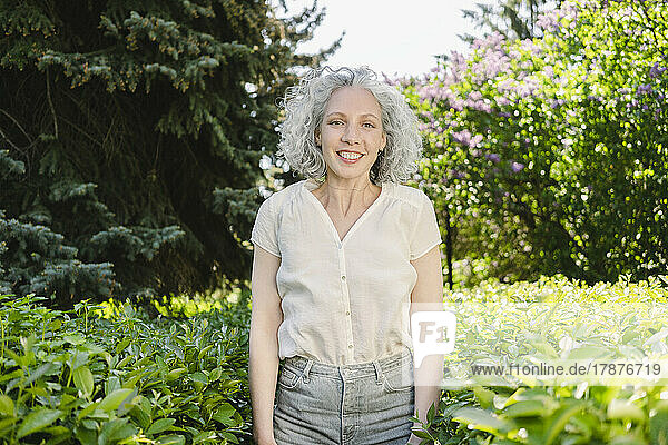 Happy woman with gray hair standing in park
