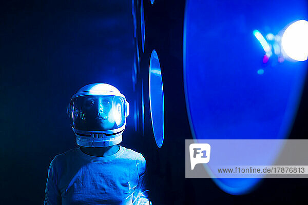 Astronaut wearing space helmet by blue illuminated light