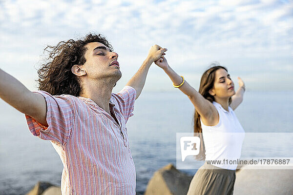 Carefree young couple holding hands standing with eyes closed