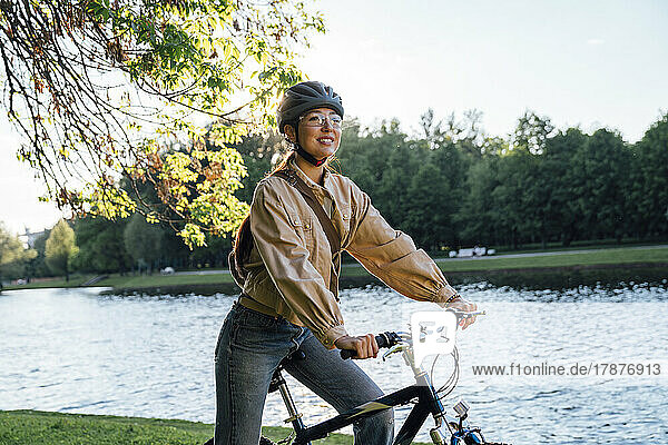 Lächelnde Frau auf dem Fahrrad am See im Park