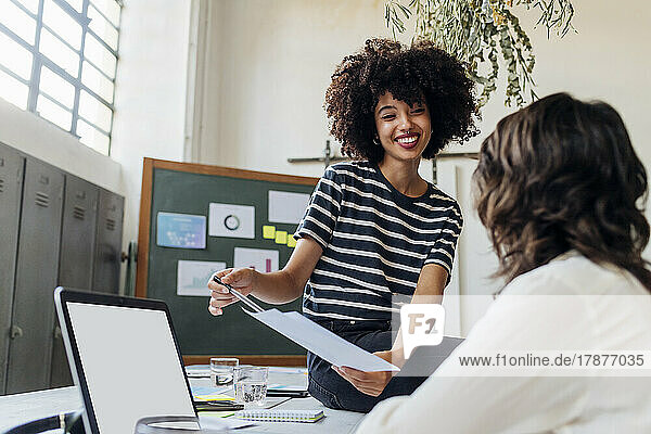 Smiling businesswoman explaining report to colleague at office