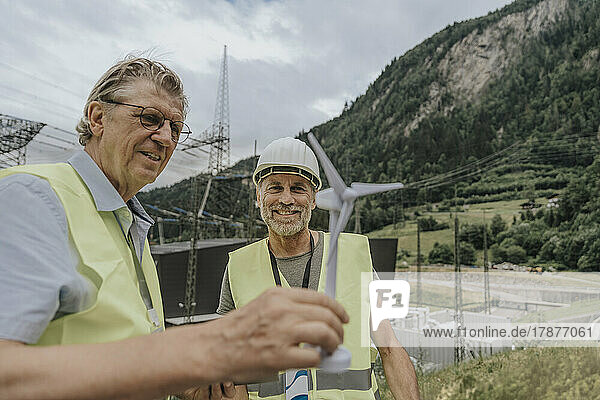 Smiling engineer discussing over wind turbine model
