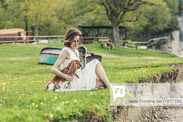 Smiling woman sitting with pet dog on grass