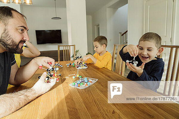 Happy boy holding molecular model by father at home