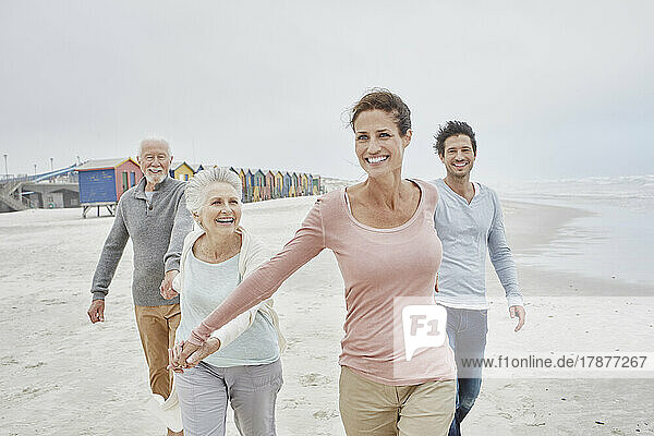 Adult couple walking with senior parents on the beach