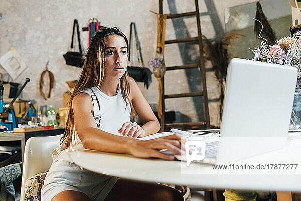Fashion designer using laptop at desk in workshop