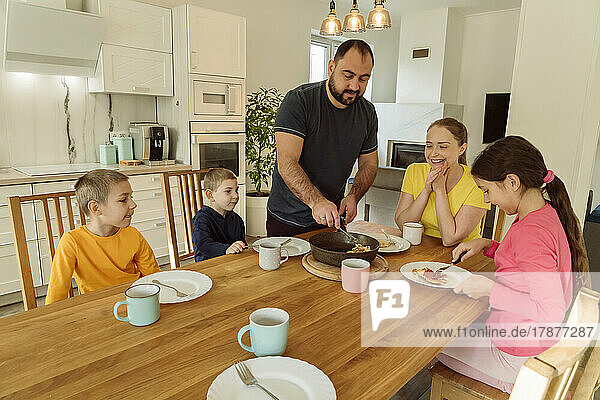 Mann serviert Familie zu Hause Frühstück