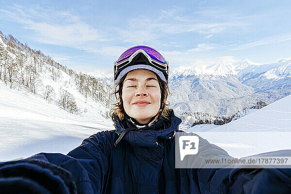 Woman with eyes closed enjoying in front of snowcapped mountains