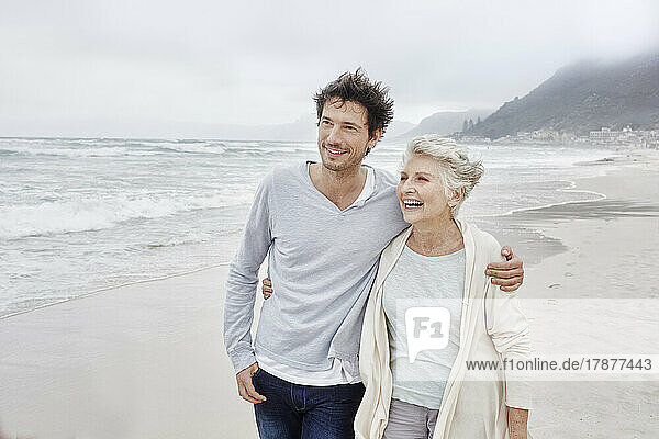 Mature man walking on the beach embracing his mother