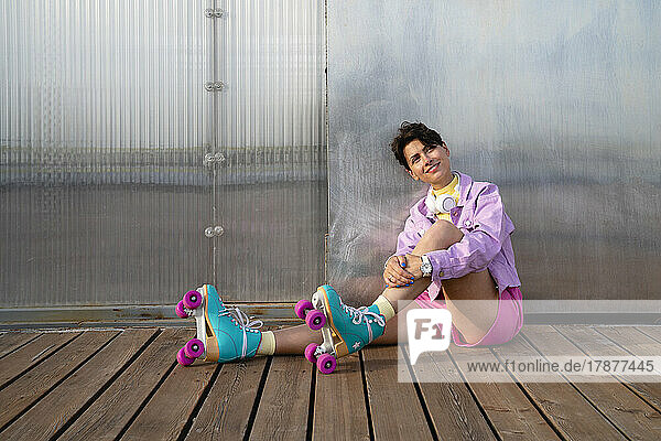 Thoughtful woman with roller skates sitting on footpath