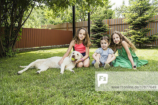 Smiling girls with dog at back yard