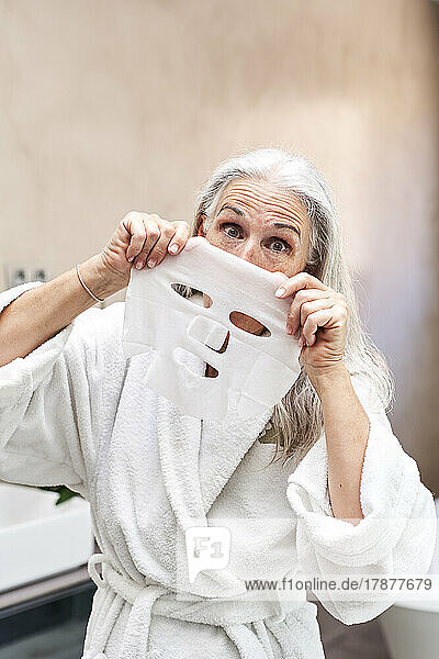 Playful woman with facial mask in bathroom