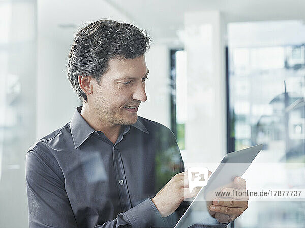 Smiling businessman using tablet PC in office