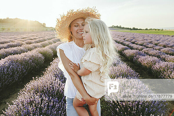 Smiling woman with daughter standing in lavender field