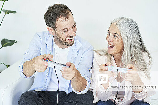 Happy mother and son playing video game with controllers at home