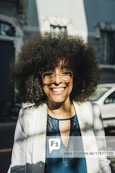 Happy businesswoman with Afro hairstyle wearing eyeglasses on sunny day