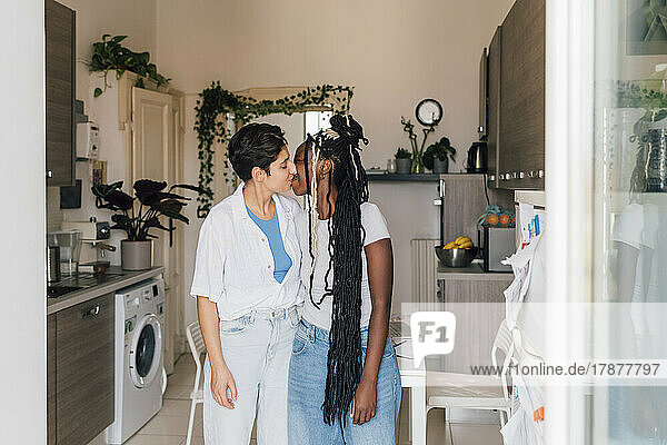 Lesbisches Paar küsst sich zu Hause in der Küche