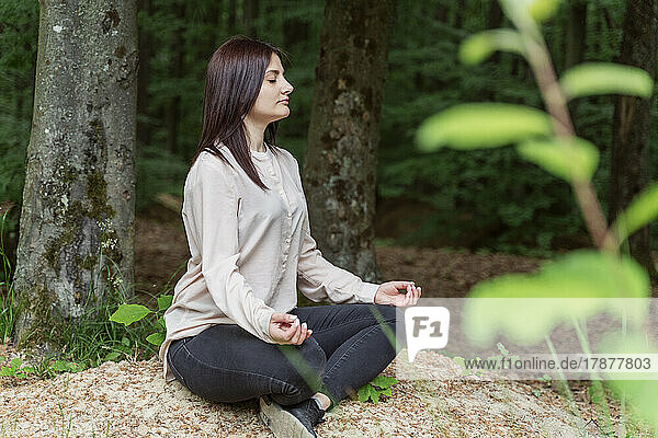 Young woman meditating in forest