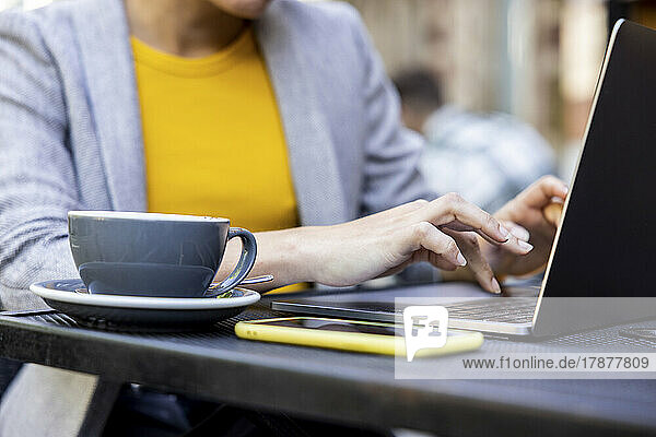 Hands of businesswoman using laptop at sidewalk cafe
