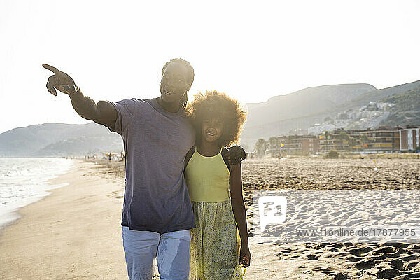 Father walking with daughter pointing at beach