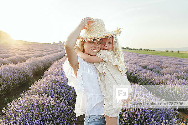 Cute girl with mother wearing hat standing in lavender field