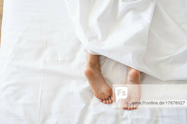 Girl lying in bed with bare feet