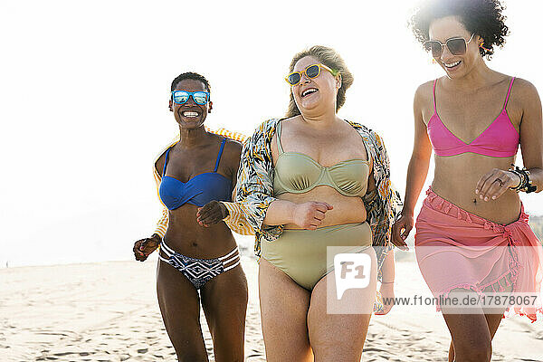 Frau mit Sonnenbrille läuft mit Freunden am Strand