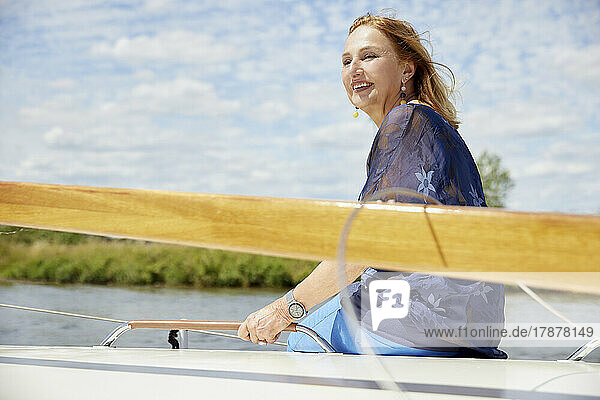 Smiling senior woman enjoying vacation sitting on deck