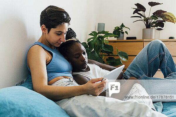 Lesbian couple watching binge through tablet PC on bed at home