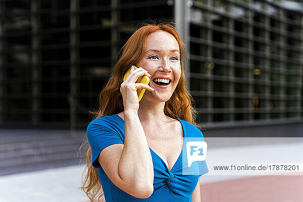 Happy woman talking on mobile phone in city