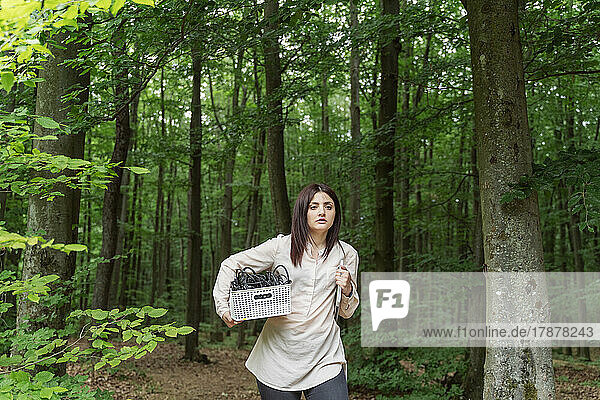 Junge Frau mit Kabelkasten spaziert im Wald