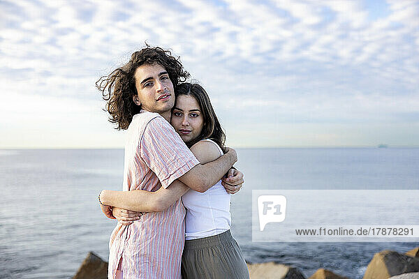 Junges Paar umarmt sich vor dem Meer