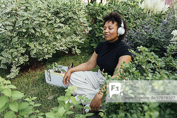 Young businesswoman with eyes closed listening music through wireless headphones at park
