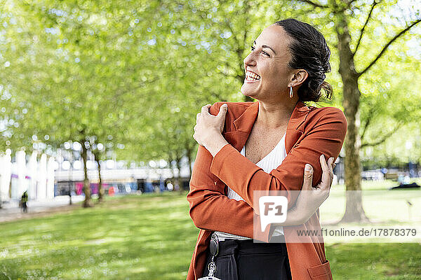 Glückliche Geschäftsfrau umarmt sich im Park