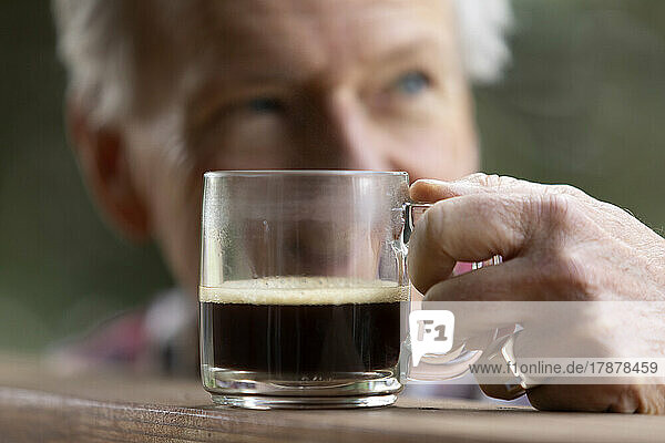 Senior man reaching for coffee cup